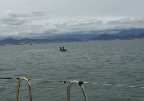 Fisherman casting net from their small boat with waves building